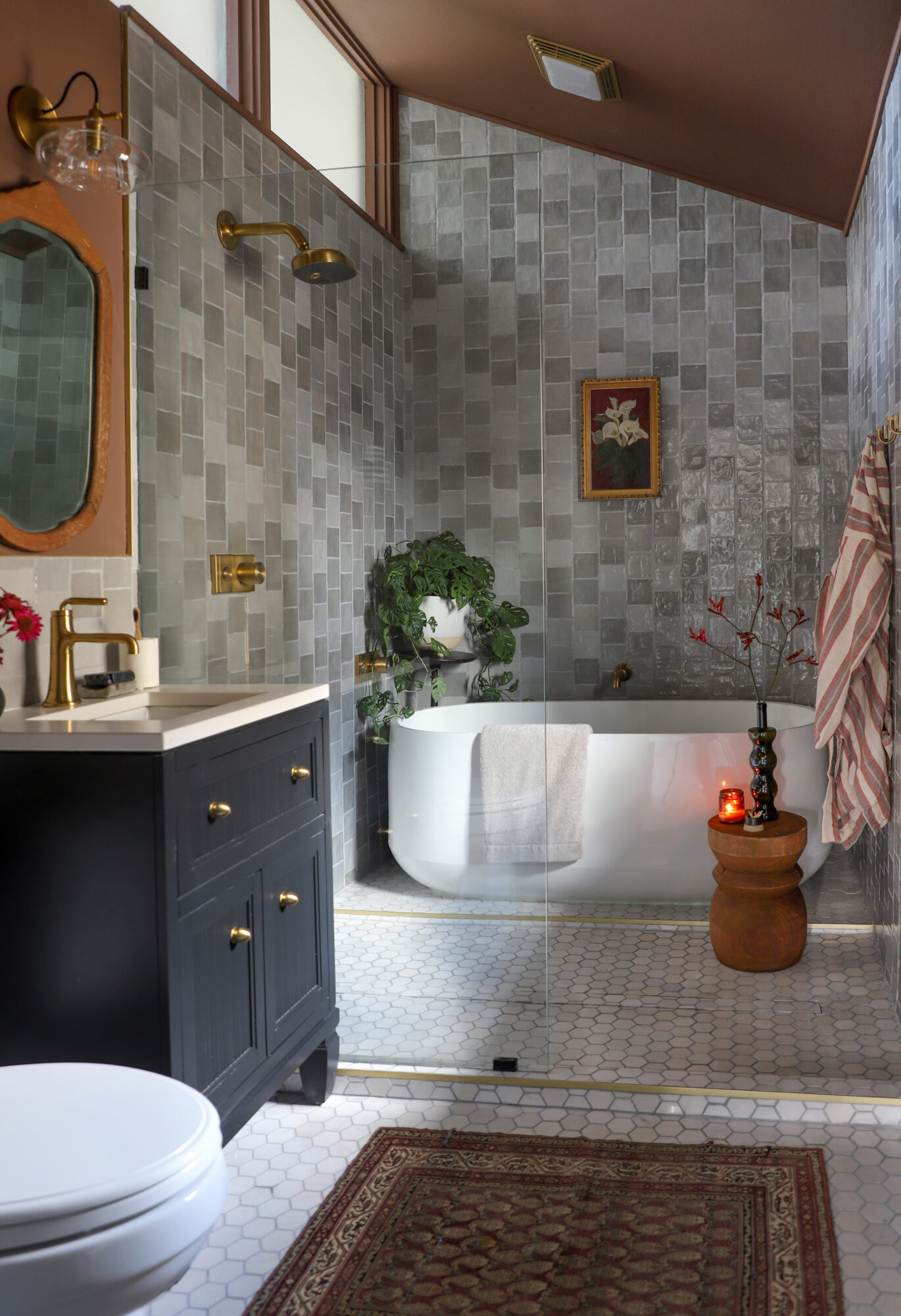 Large bathroom with tiled walls and flooring that has touches of warm accents from accessories.