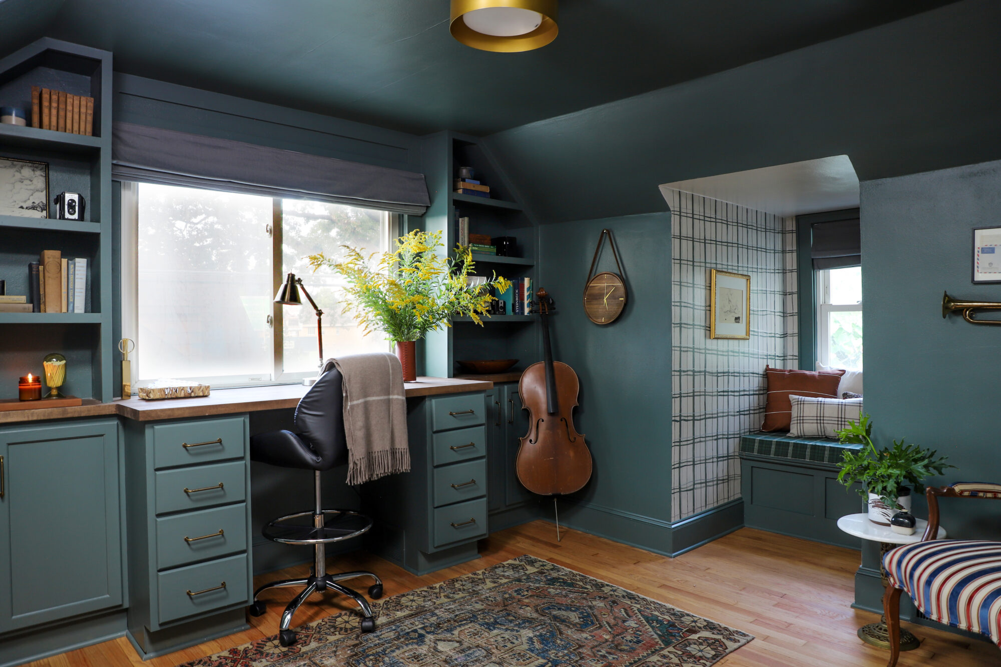 Beautiful home office with moody green walls, a built-in desk, and window nook for reading.